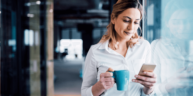 Woman holding a coffee mug and using her smartphone